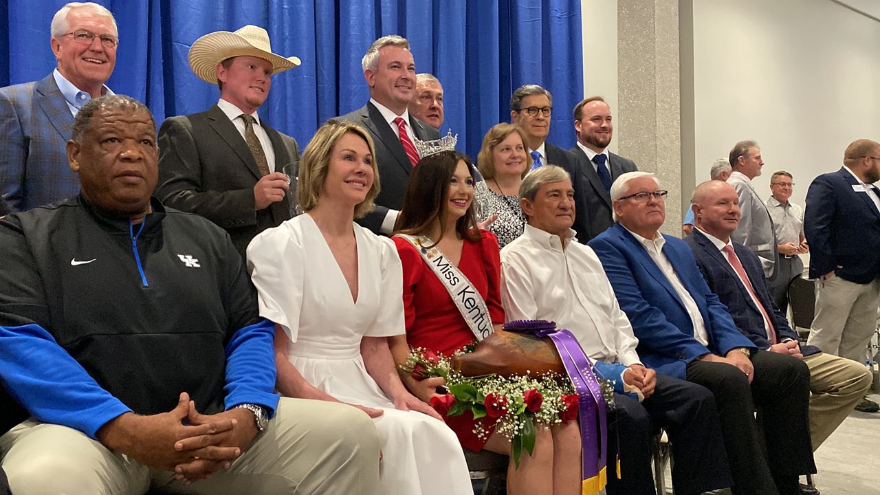 Kelly Craft (white dress) sits next to Miss Kentucky 2022, Hanna Edelen, who holds the record-shattering $5 million country ham (Spectrum News 1/Diamond Palmer)