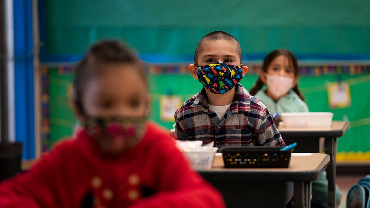 Children wearing masks in a classroom.