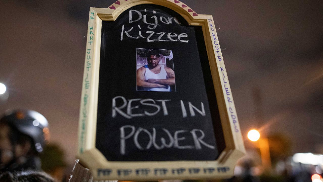 A protester holds a sign with a picture of Dijon Kizzee, who died after being shot by deputies of the Los Angeles Sheriff's Department on Monday, Aug. 31, 2020, in Los Angeles, Calif. (AP Photo/Christian Monterrosa)