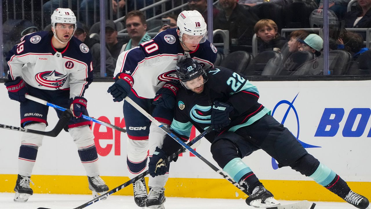 Seattle Kraken right wing Oliver Bjorkstrand (22) loses his footing against Columbus Blue Jackets left wing Dmitri Voronkov (10) while vying for the puck during the second period of an NHL hockey game Tuesday, Nov. 12, 2024, in Seattle. (AP Photo/Lindsey Wasson)