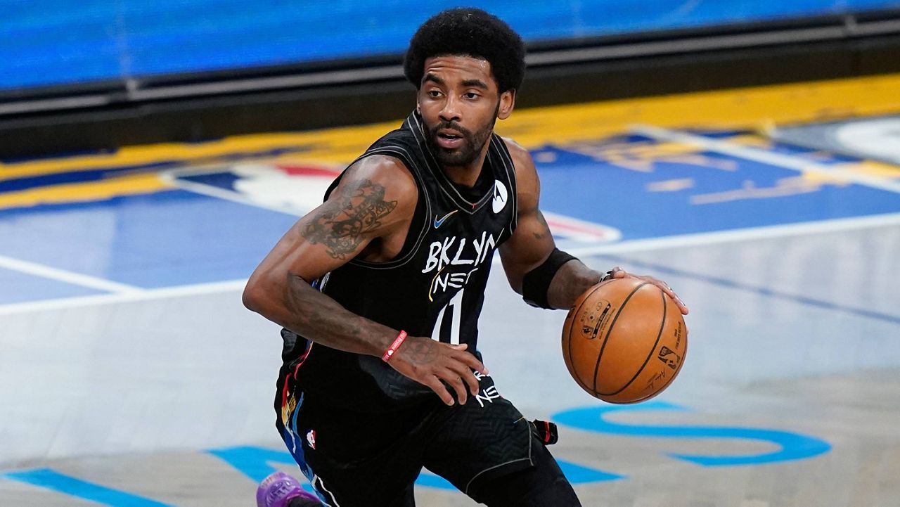 Kyrie Irving of the Brooklyn Nets, wearing a black jersey, drives with a basketball in a left hand.