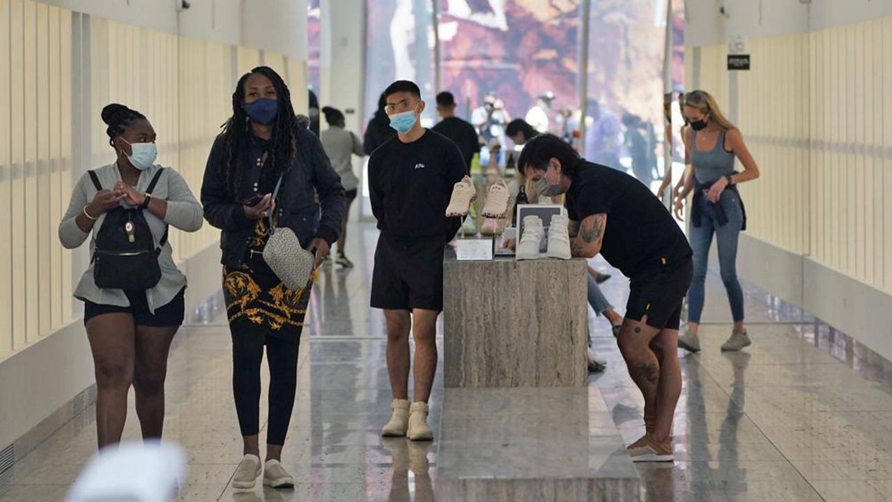 In this May 20, 2021 file photo workers and customers wear masks amid the COVID-19 pandemic inside a shoe store, in Los Angeles. (AP Photo/Marcio Jose Sanchez,File)
