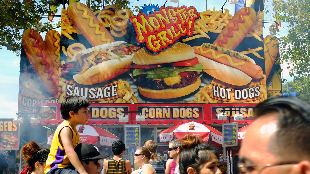 Fairgoers pass the Monster Grill one of the many food stalls at the LA County Fair on Labor Day in Pomona Calif. on Monday Sept. 2, 2013. (AP Photo/Richard Vogel)