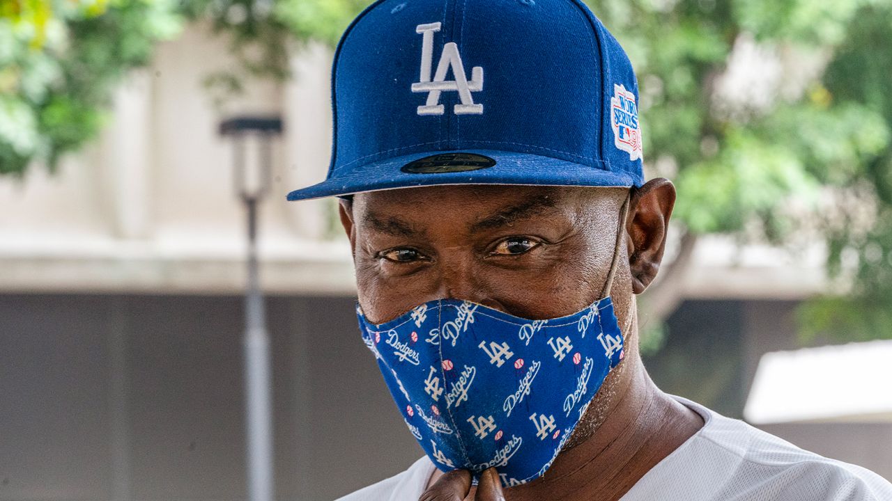 Wayne Avery, a Los Angeles Dodgers fan since 1964, wears a Dodgers' face mask as he wishes fellow Angelenos would get vaccinated, in downtown Los Angeles, Monday, July 26, 2021. (AP Photo/Damian Dovarganes)