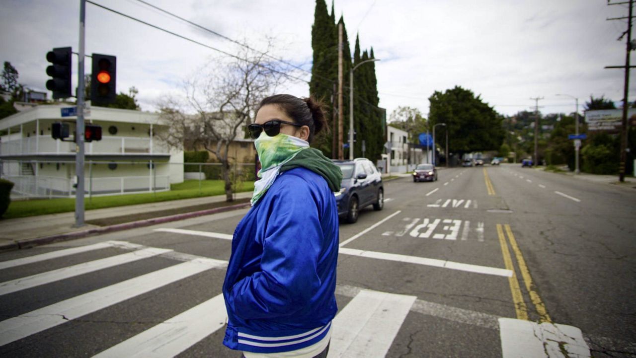 A woman ccrosses the street early during the pandemic in this image from LAPL's COVID-19 archive. (Tara Parian, A COVID-19 Community Archive, Los Angeles Public Library Special Collections)