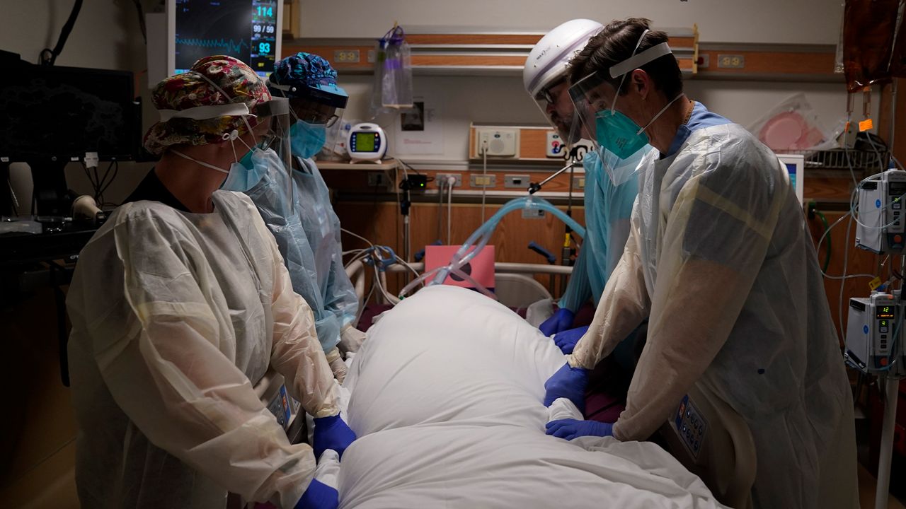 In this Dec. 22, 2020, file photo, medical workers prepare to manually prone a COVID-19 patient in an intensive care unit at Providence Holy Cross Medical Center in the Mission Hills section of Los Angeles. California surpassed 25,000 coronavirus deaths since the start of the pandemic, reporting the grim milestone Thursday, Dec. 31, 2020, as it continues to face a surge that has swamped hospitals and pushed nurses and doctors to the breaking point as they brace for an anticipated surge after the holidays. (AP Photo/Jae C. Hong, File)