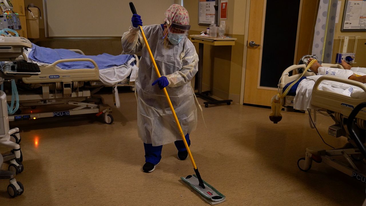 Hospital worker Alma Garibay mops the floor of a COVID-19 unit at Providence Holy Cross Medical Center in the Mission Hills section of Los Angeles, Tuesday, Dec. 22, 2020. (AP Photo/Jae C. Hong)