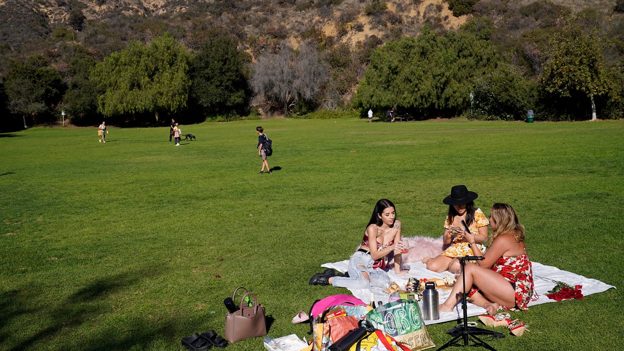 Friends Carolina Santos, left, Itly Thayieng, middle, and Carolyn Lee enjoy the hot weather with a picnic at the Lake Hollywood Park in Los Angeles on Thursday, Nov. 11, 2021. (AP Photo/Damian Dovarganes)