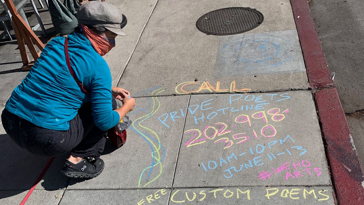 Pride Poet cohort member Jen Chang drops a chalk art advertisement for this weekend's poetry hotline. (Photo courtesy Brian Sonia-Wallace)