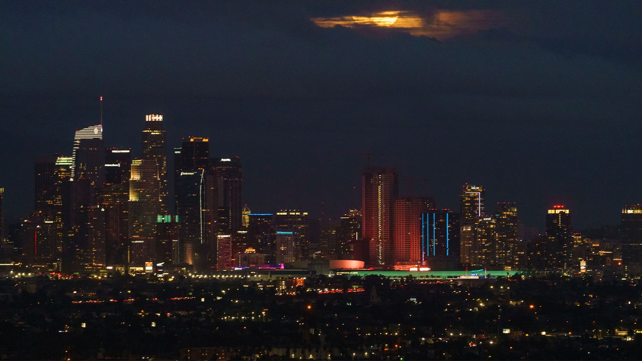 A full moon rises behind heavy clouds over the Los Angeles skyline, seen from Kenneth Hahn State Recreational Area, in Los Angeles Thursday, Jan. 28, 2021. (AP Photo/Damian Dovarganes)