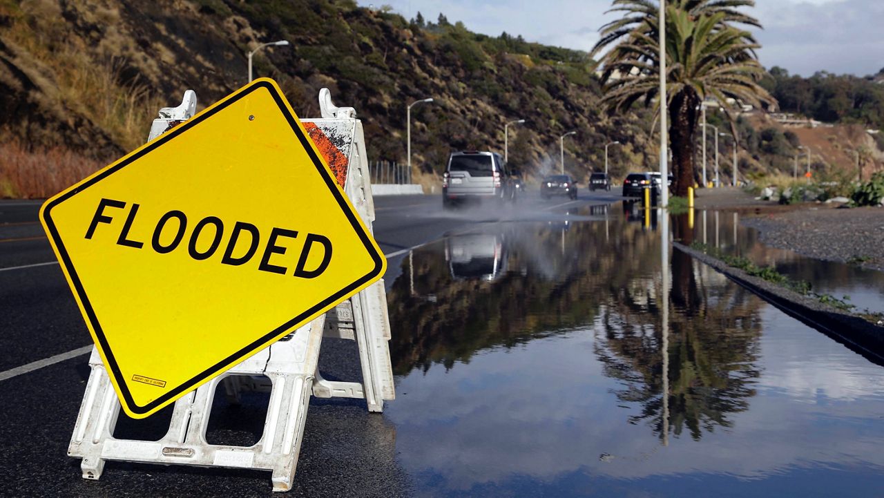 A sign warning of flooded road is posted along the Pacific Coat Highway in Malibu, Calif.  after a heavy rain on Tuesday, Jan. 5, 2016. (AP Photo/Nick Ut)