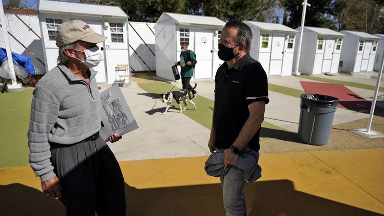 Hope of the Valley CEO Ken Craft, right, talks to resident Ted Beauregard outside of a row of tiny homes for the homeless, Thursday, Feb. 25, 2021, in the North Hollywood section of Los Angeles. (AP Photo/Marcio Jose Sanchez)