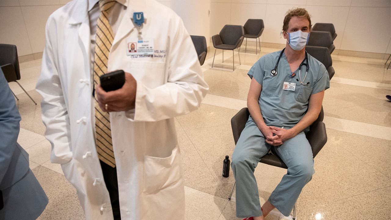 UCLA physician Russell Johnson, right, sits as he waits for a half hour for any side effects after getting an injection of the Covid-19 vaccine at Ronald Reagan UCLA Medical Center on Wednesday, Dec. 16, 2020 in Westwood, CA. (Brian van der Brug/Los Angeles Times via AP, Pool)
