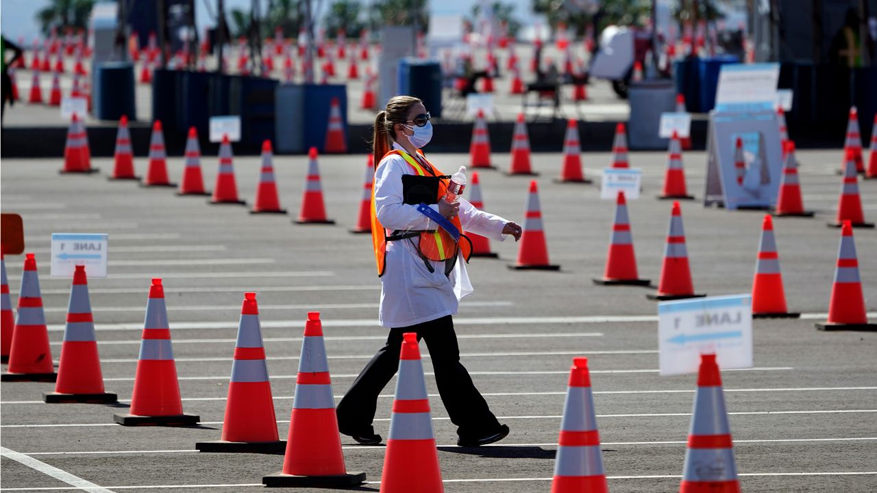 Sossie Bedrossian, head of nursing for the Los Angeles school district, walks in the parking lot of a COVID-19 vaccination site for district employees at SOFI Stadium Tuesday, March 2, 2021, in Inglewood, Calif. (AP Photo/Marcio Jose Sanchez)