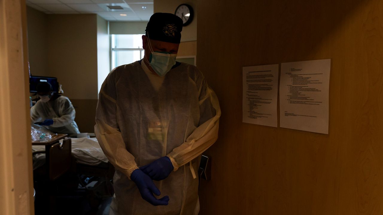 Respiratory therapist Frans Oudenaar, walks out of a room after he helped provide postmortem care for a COVID-19 victim at Providence Holy Cross Medical Center in Los Angeles, Dec. 14, 2021. (AP Photo/Jae C. Hong)