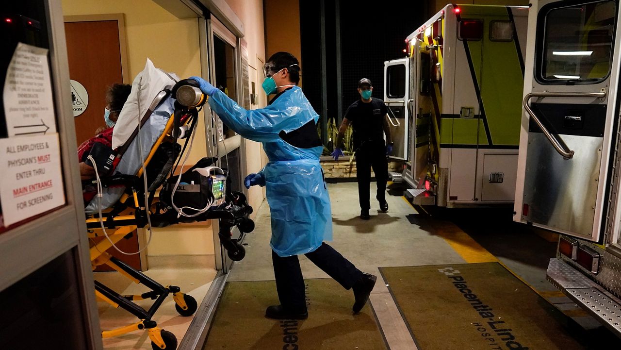 Emergency medical technician Thomas Hoang, 29, of Emergency Ambulance Service, pushes a gurney into an emergency room to drop off a COVID-19 patient in Placentia, Calif., Friday, Jan. 8, 2021. (AP Photo/Jae C. Hong, File)