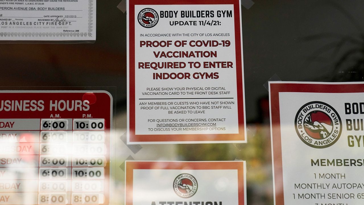 A sign requiring members to show proof of COVID-19 vaccination to enter the gym is posted on the window of Body Builders Gym Monday, Nov. 8, 2021, in Los Angeles. (AP Photo/Jae C. Hong)