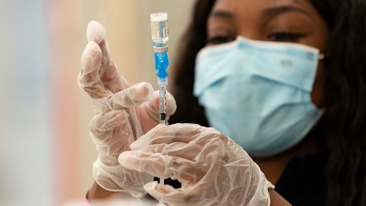 A woman preparing the COVID-19 vaccine while wearing a mask. (AP Images)