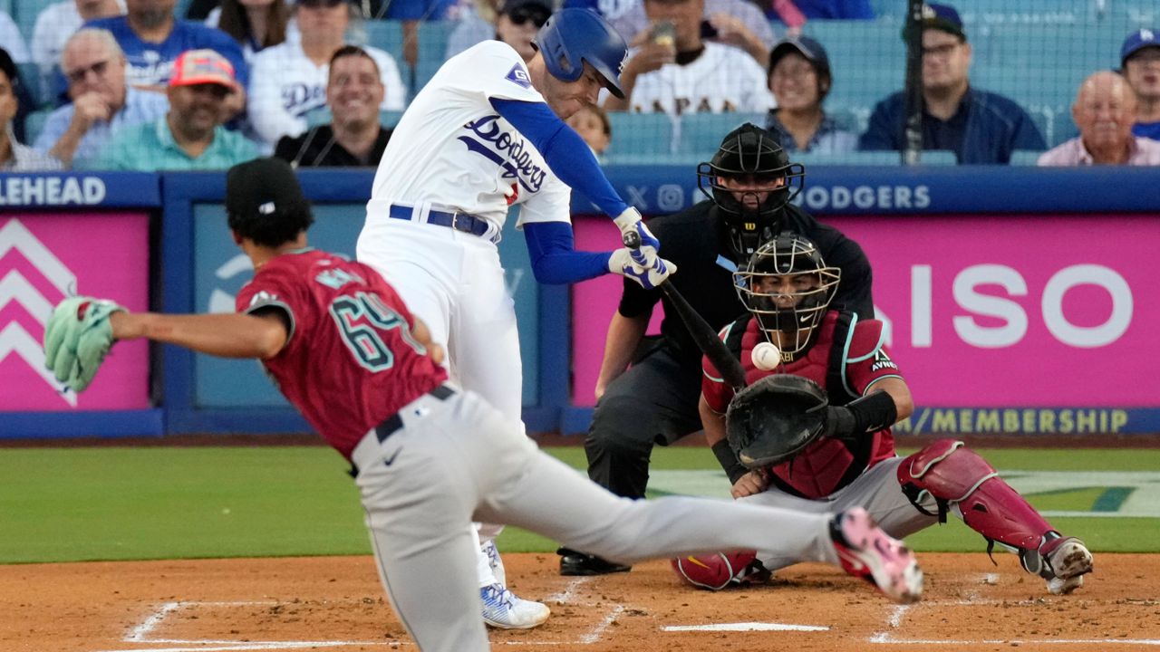 Los Angeles Dodgers' Freddie Freeman, second from left, hits a three-run home run as Arizona Diamondbacks starting pitcher Cristian Mena, left, and catcher Gabriel Moreno, right, watch along with home plate umpire Jordan Baker during the first inning of a baseball game Wednesday in LA. (AP Photo/Mark J. Terrill)