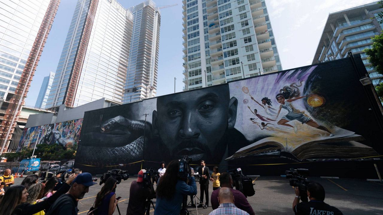 Members of the media gather in front of a mural depicting Kobe Bryant and his daughter, Gianna, during a news conference in Los Angeles, Aug. 24, 2022. (AP Photo/Jae C. Hong)