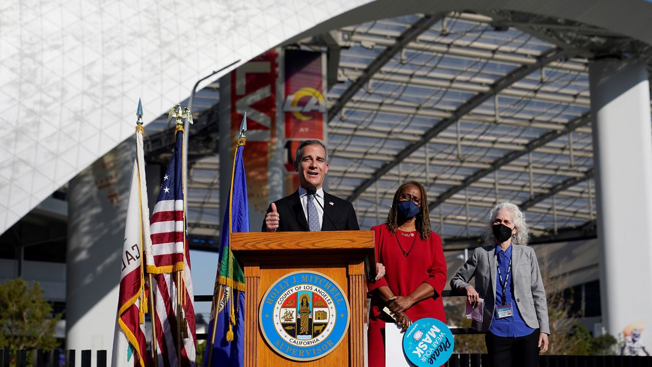 Los Angeles Mayor Eric Garcetti, at podium, speaks as LA County Supervisor Holly J. Mitchell, in red, and LA County Department of Public Health Director Dr. Barbara Ferrer listen during a news conference near SoFi Stadium Wednesday in Inglewood, Calif. (AP Photo/Marcio Jose Sanchez)