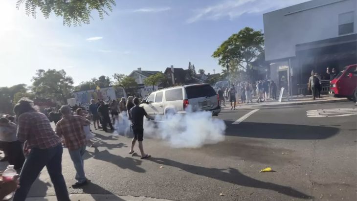 A flash-bang grenade is used as immigration agents work to disperse a crowd near Buona Forchetta in San Diego on Friday. (KPBS /AP Lara Azevedo-McCaffrey)