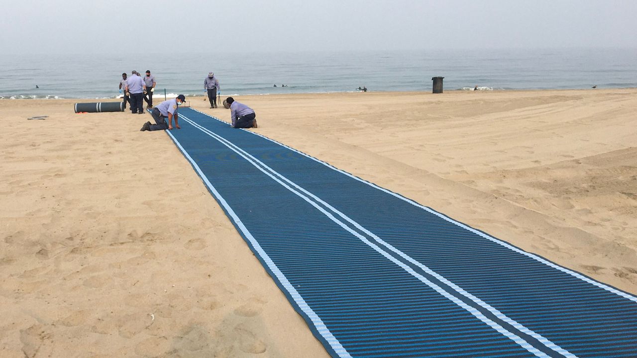 Crews from the Los Angeles County Department of Beaches and Harbors install a semi-permanent access mat at Torrance Beach. (LA County Dept. of Beaches and Harbors)