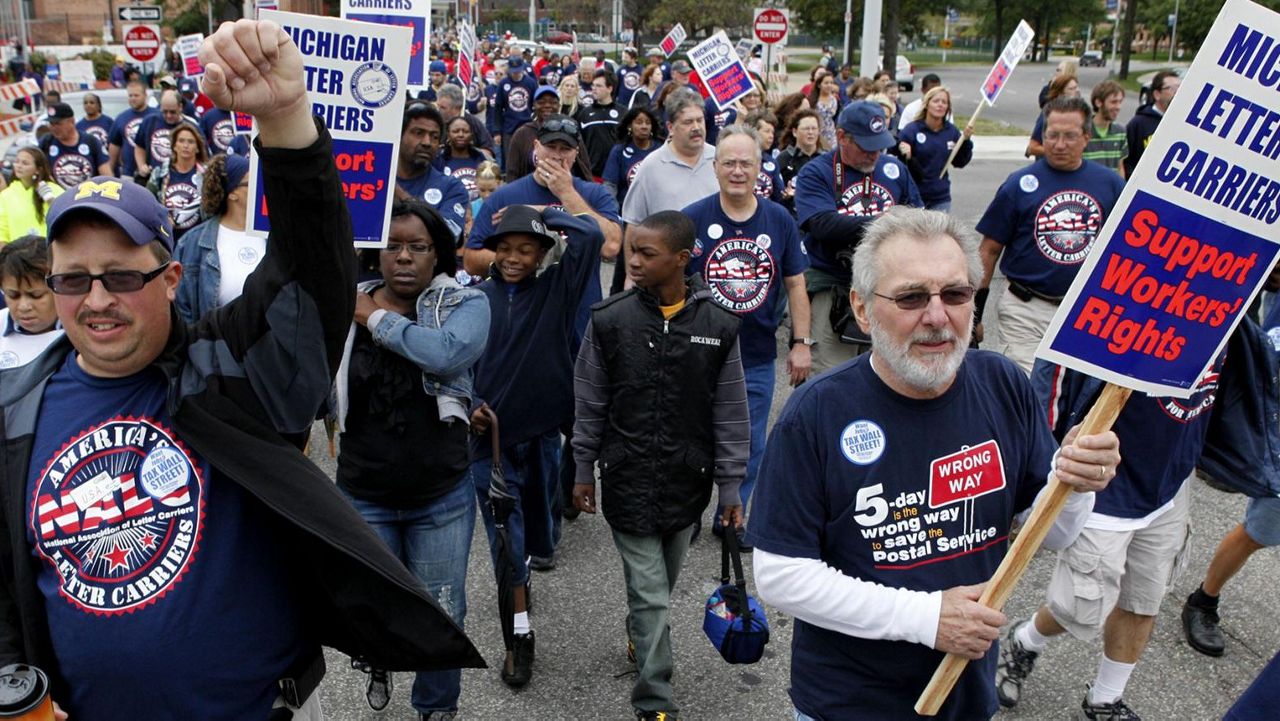 Union members hold signs as they walk in the annual Labor Day parade in Detroit, Michigan. (Associated Press)