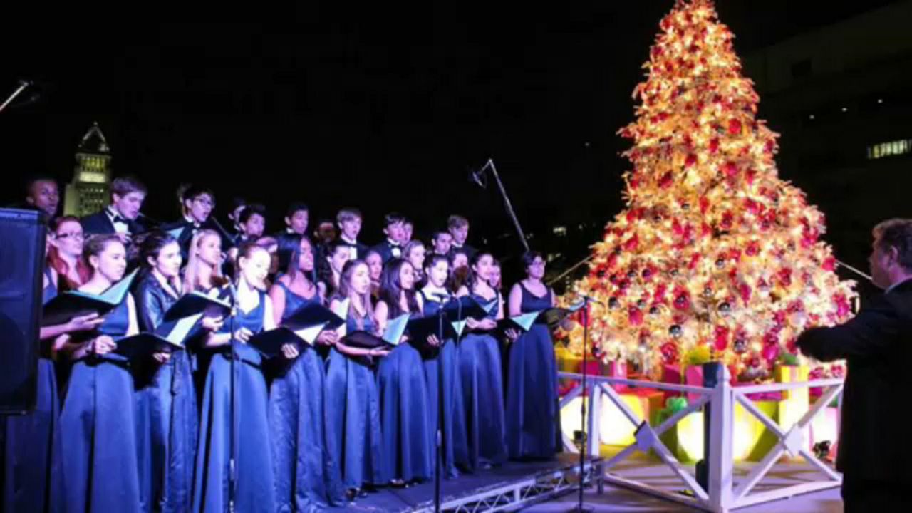 a choir singing next to a Christmas tree