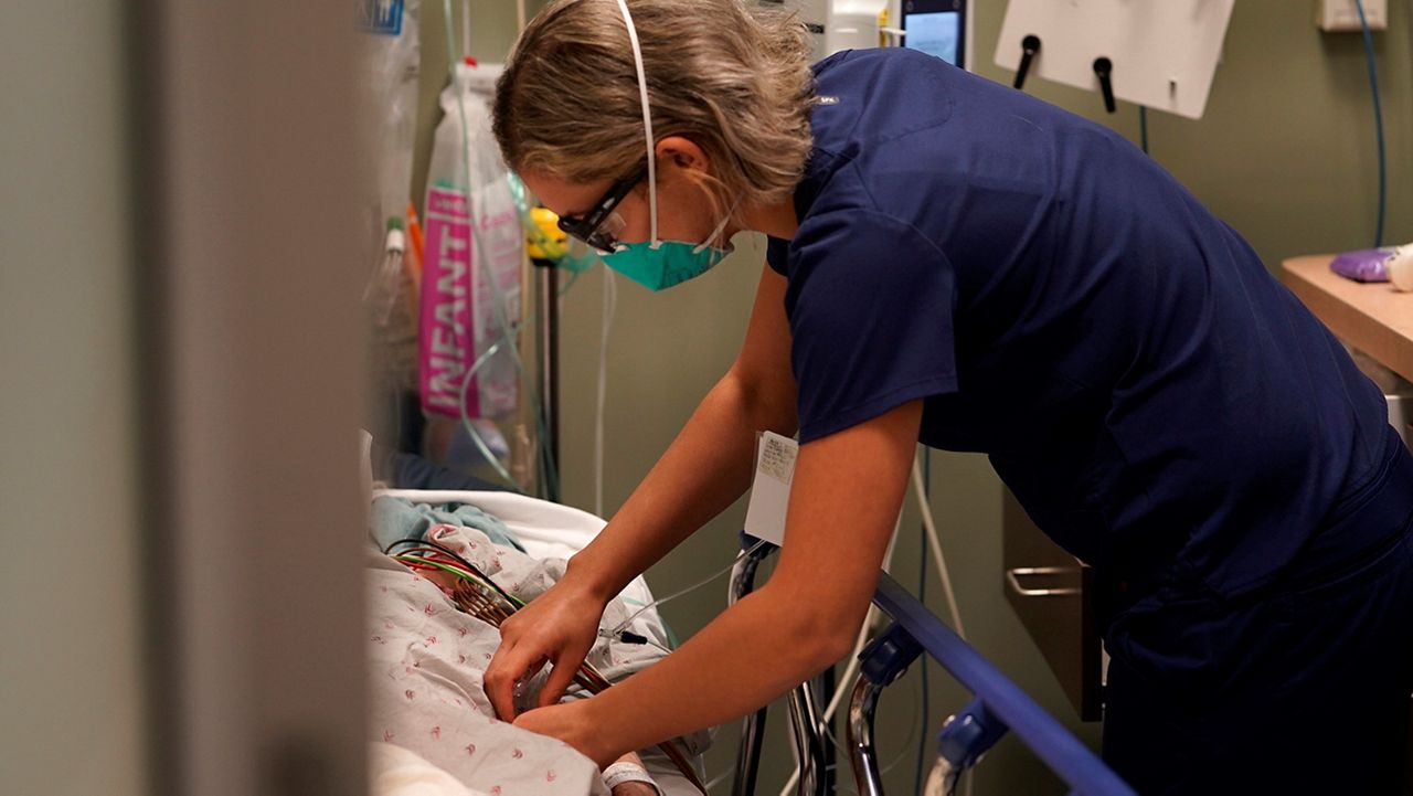 Registered nurse Sandra Younan adjusts an intravenous line for a patient at the emergency room of Providence Cedars-Sinai Tarzana Medical Center in the Tarzana neighborhood of Los Angeles on Thursday, March 11, 2021. Younan spent the last year juggling long hours as she watched many patients struggle with the coronavirus and some die. Then there were the patients who claimed the virus was fake or coughed in her face, ignoring mask rules. One man stormed out of the hospital after a positive COVID-19 test, refusing to believe it was accurate. (AP Photo/Damian Dovarganes)