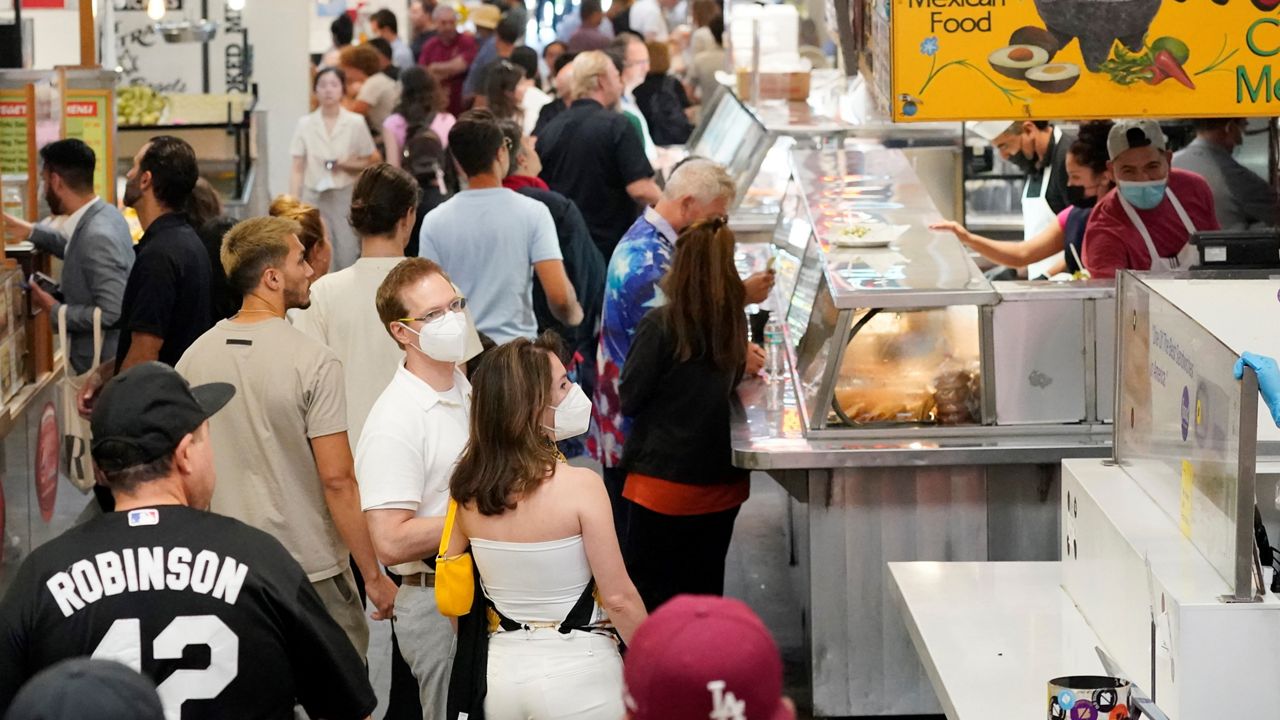 Mask an unmasked patrons walk along a row of food stands inside Grand Central Station Wednesday, July 13, 2022, in Los Angeles. Los Angeles County might be imposing a mandate on July 29 if COVID-19 numbers continue to rise. (AP Photo/Marcio Jose Sanchez)