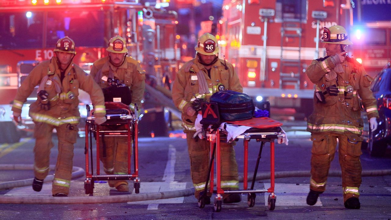 Los Angeles Fire Department firefighters push gurneys at the scene of a structure fire that injured multiple firefighters, May 16, 2020. (AP Photo/Damian Dovarganes, File)