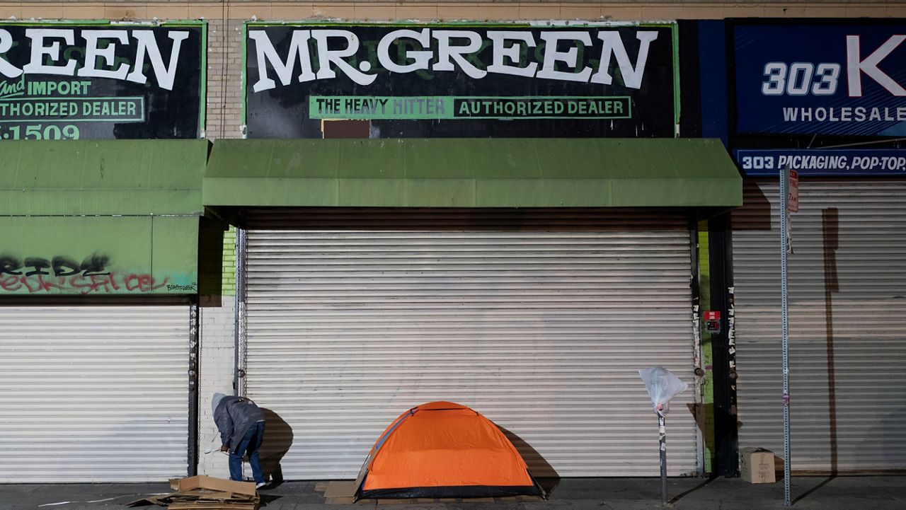 A homeless man stands next to his tent in Los Angeles, Wednesday, Dec. 14, 2022. (AP Photo/Jae C. Hong)