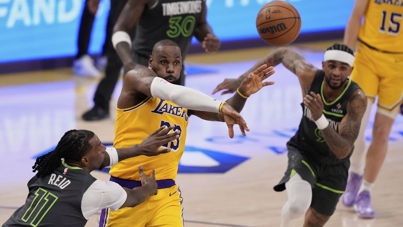 Los Angeles Lakers forward LeBron James, center, passes the ball as Minnesota Timberwolves center Naz Reid, left, and guard Nickeil Alexander-Walker defend during the second half in Game 5 of an NBA basketball first-round playoff series Wednesday, April 30, 2025, in Los Angeles. (AP Photo/Mark J. Terrill)