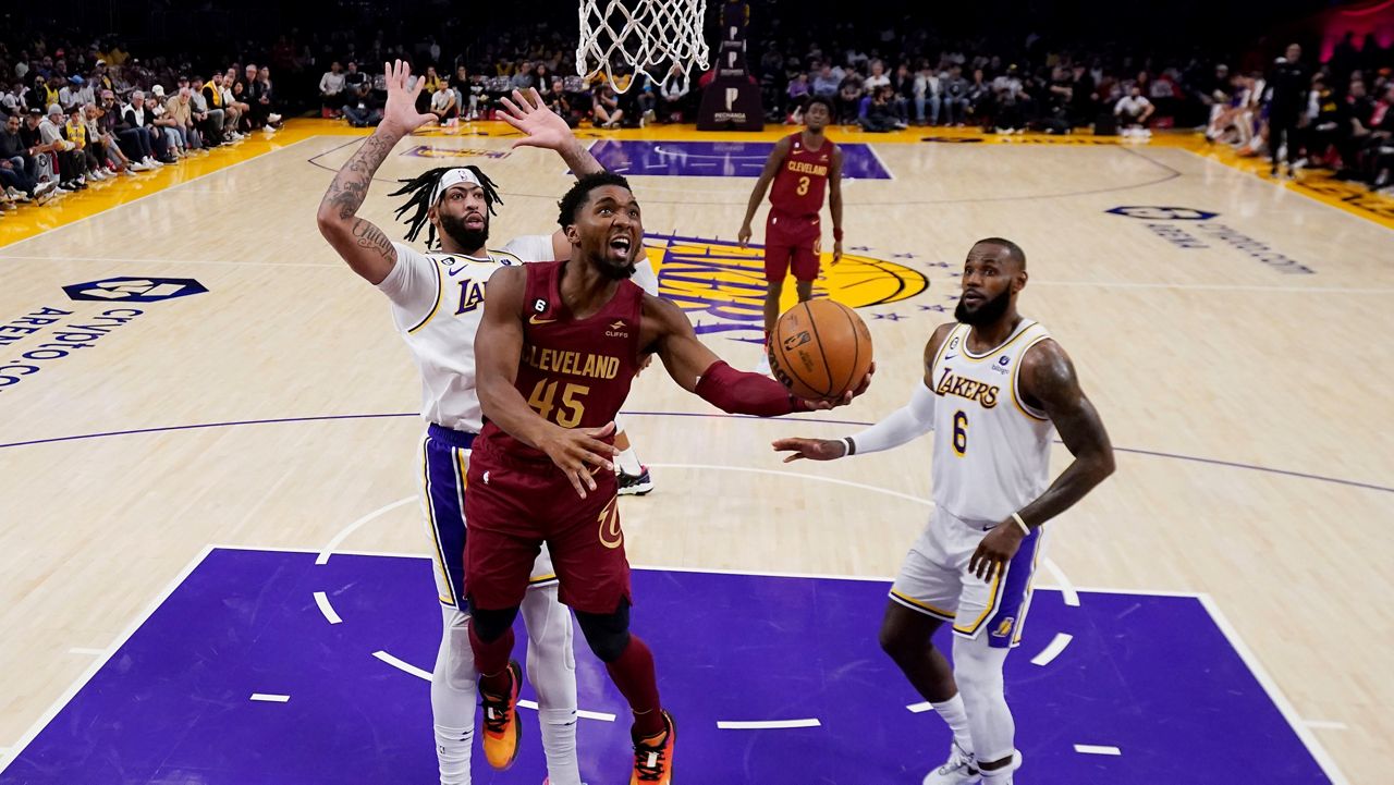 Cleveland Cavaliers guard Donovan Mitchell (45) drives past Los Angeles Lakers forward Anthony Davis, left, and forward LeBron James during the first half of an NBA basketball game Sunday, Nov. 6, 2022, in Los Angeles. (AP Photo/Marcio Jose Sanchez)