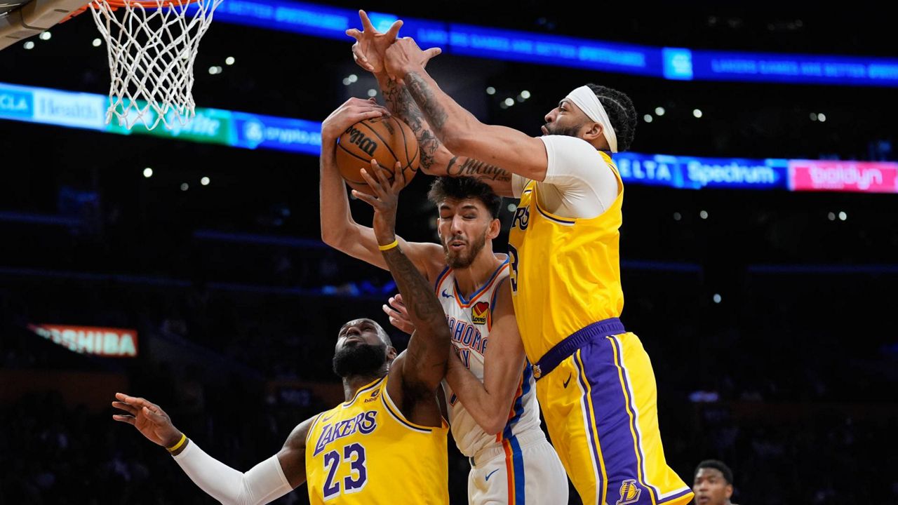 Oklahoma City Thunder forward Chet Holmgren, center, works for a rebound between Los Angeles Lakers forward LeBron James (23) and forward Anthony Davis during the first half of an NBA basketball game Monday in LA. (AP Photo/Marcio Jose Sanchez)