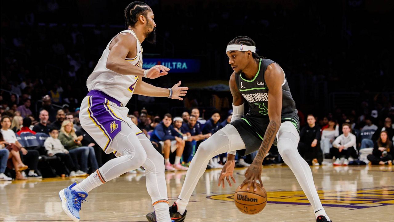 Minnesota Timberwolves forward Jaden McDaniels (3) dribbles past Los Angeles Lakers guard Spencer Dinwiddie (26) during the first half of an NBA basketball game Sunday in LA. (AP Photo/Etienne Laurent)