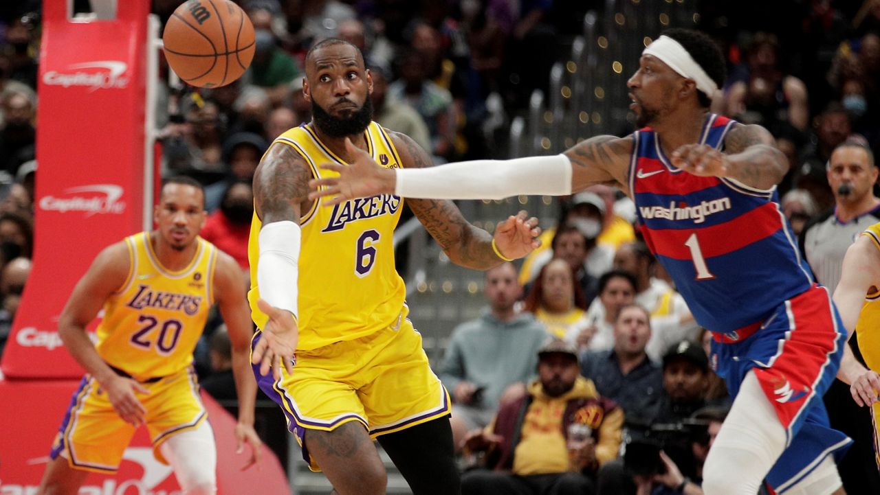 Los Angeles Lakers' LeBron James (6) and Washington Wizards' Kentavious Caldwell-Pope (1) reach for the ball during the second half of an NBA basketball game, Saturday, March 19, 2022, in Washington. (AP Photo/Luis M. Alvarez)