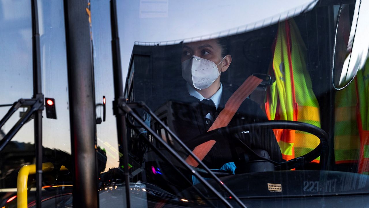 A Metro Transit bus driver wears an N95 protective mask and gloves as she drives her bus near Staples Center in downtown Los Angeles, Monday, Jan. 25, 2021. (AP Photo/Damian Dovarganes)
