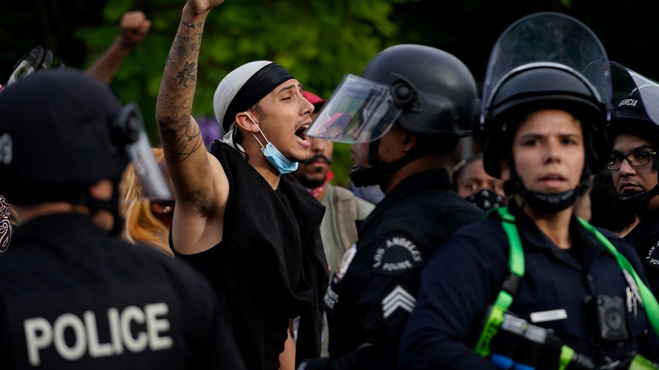 Khalil Mitchell tries to redirect the crowd as they are rerouted by police officers on Monday, June 1, 2020, in the Hollywood area of Los Angeles during a protest over the death of George Floyd. Floyd died in police custody on Memorial Day in Minneapolis. (AP Photo/Ashley Landis)