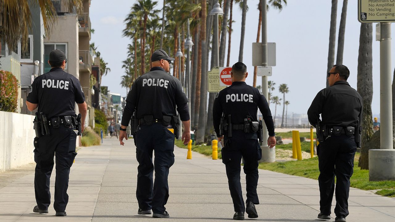 In this March 28, 2020, file photo, Los Angeles police officers patrol a sparsely populated Venice Beach boardwalk in Los Angeles. (AP Photo/Mark J. Terrill, File)