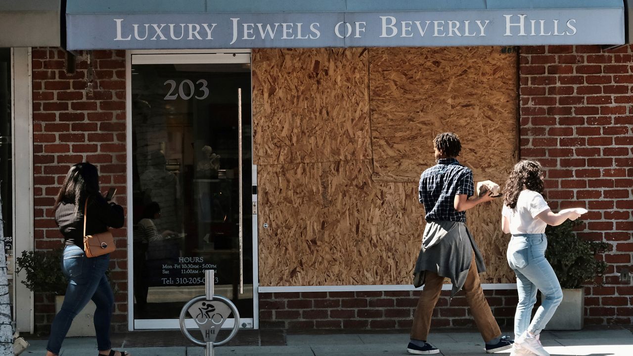 Pedestrians walk past a boarded up Luxury Jewels of Beverly Hills on Wednesday, March 23, 2022 in Beverly Hills, Calif. (AP Photo/Richard Vogel)