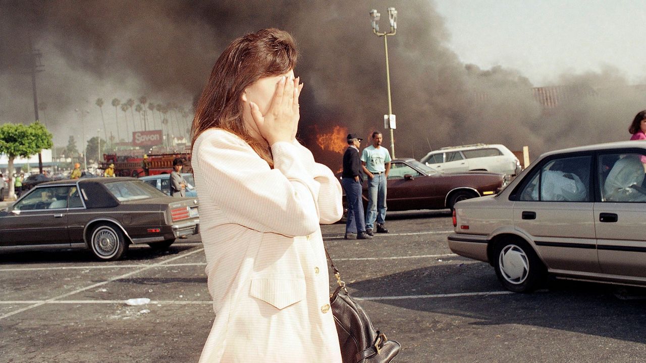 An unidentified owner of a clothing store reacts to seeing her burning business in Los Angeles, Thursday, April 30, 1992. Her store was one of more than 300 burned by rioters after the acquittal of four police officers on Wednesday in the Rodney King beating trial. (AP Photo/Nick Ut)