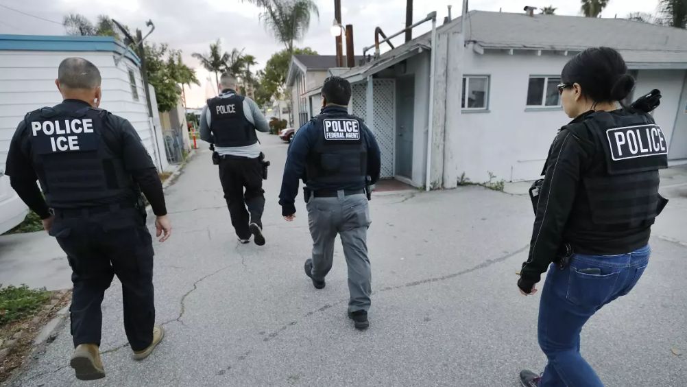 Immigration enforcement agents advance walk through a neighborhood. (Los Angeles Times/Al Seib)