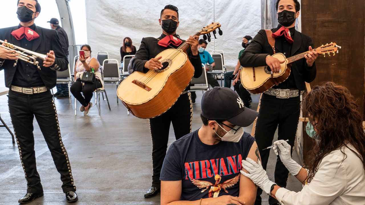 Musician Chava Ilizaliturri, with the band Migrant Motel, originally from Ciudad de Mexico, is vaccinated by registered nurse Annette Gerosa, as the Mariachi Serenade performs at the Mexican Consulate in Los Angeles Saturday, May 8, 2021. (AP Photo/Damian Dovarganes)