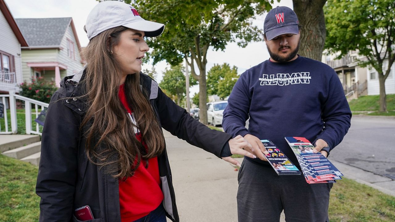 FILE - Diego Rebollar and Andreina Patilliet canvas a Hispanic neighborhood with Republican literature in Milwaukee, on Friday, Oct. 7, 2022. (AP Photo/Morry Gash)