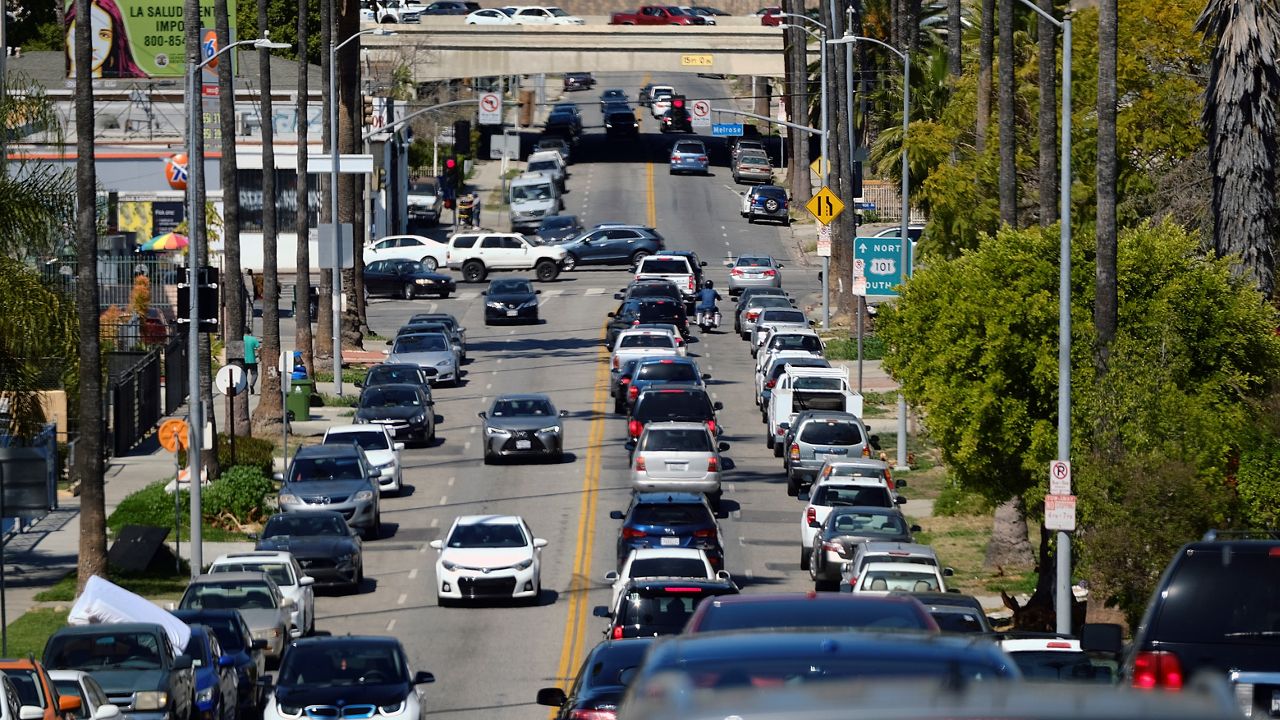 A backed up line of traffic winds its way along a street near downtown Los Angeles on Sunday, March 28, 2021. (AP Photo/Richard Vogel)