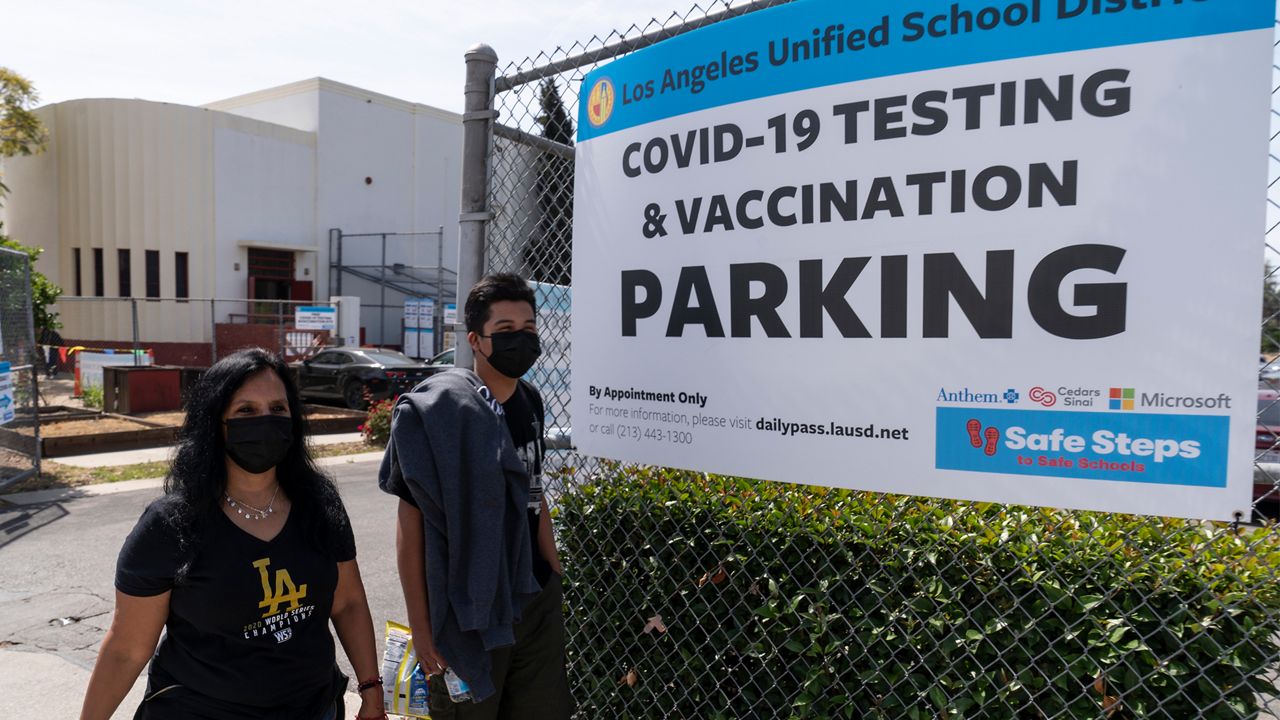 In this April 15, 2021, file photo, parent Rosa Vargas and her son, 9th grade student Victor Loredo, 14, walk home after getting tested at an LAUSD COVID-19 testing and vaccination site in East Los Angeles. (AP Photo/Damian Dovarganes)