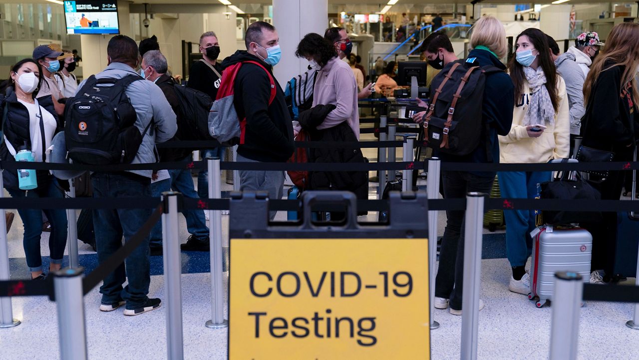 Travelers wait in line for screening near a sign for a COVID-19 testing site at the Los Angeles International Airport in Los Angeles on Nov. 24, 2021. (AP Photo/Jae C. Hong, File)