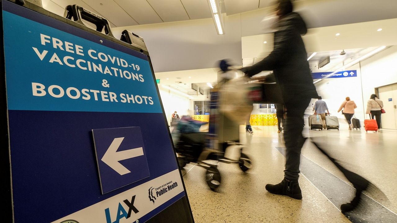 A sign pointing to free COVID-19 vaccinations and booster shots is posted at Los Angeles International Airport on Dec. 22, 2021. (AP Photo/Ringo H.W. Chiu)